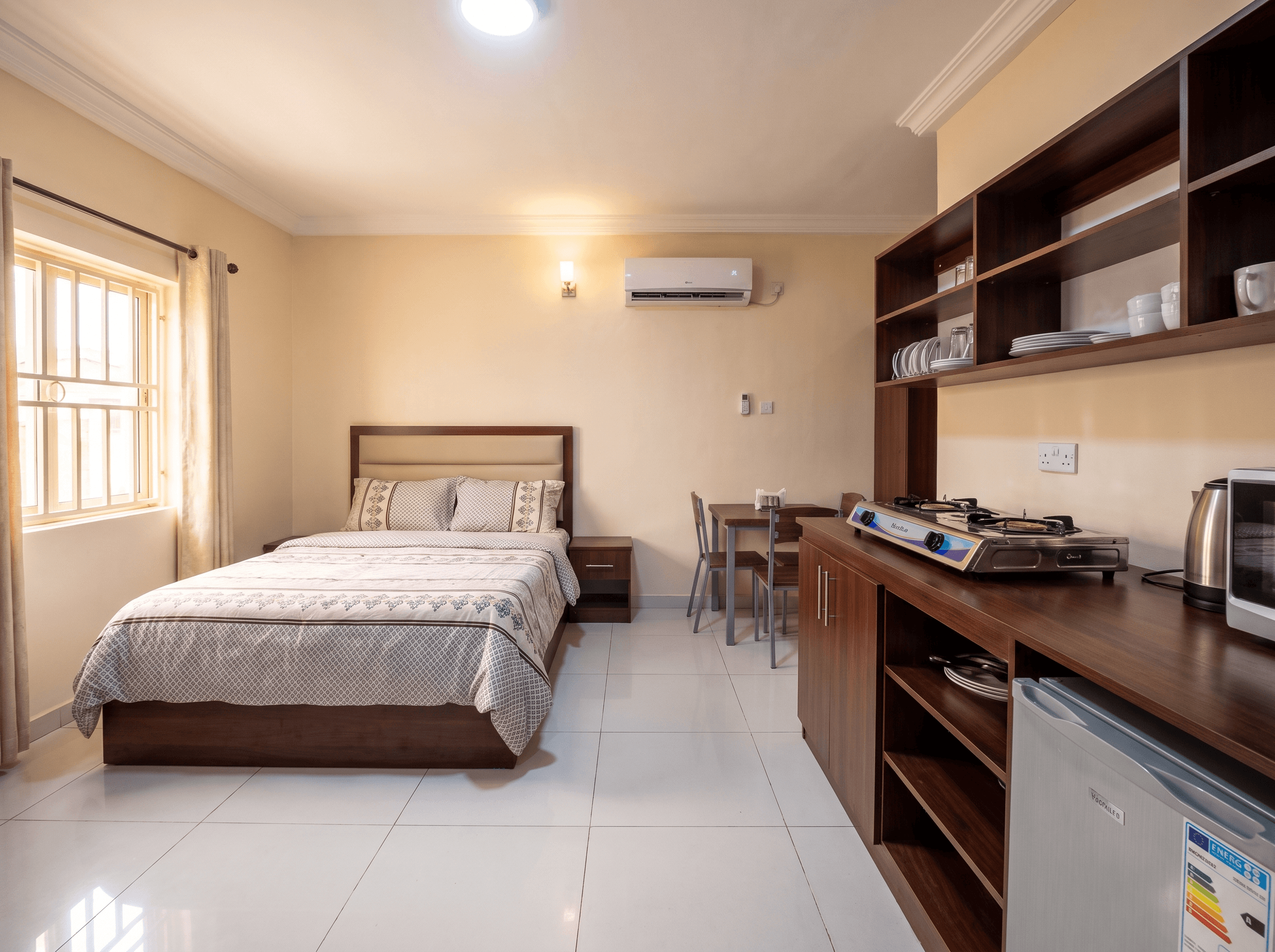 A serviced studio with a made bed, wardrobe and kitchenette